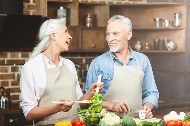 Lachendes Paar, das sich anschaut, während es in der Küche Essen zubereitet