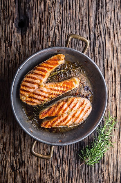 Lachs. Gegrillter Fischlachs. Gegrilltes Lachssteak in gebratener Pfanne auf rustikalem Holztisch.