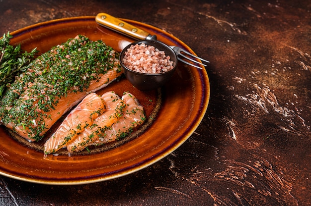 Lachs Gravlax geheilt mit Dill und rosa Salz auf rustikalem Teller. Dunkler Hintergrund. Ansicht von oben. Platz kopieren.