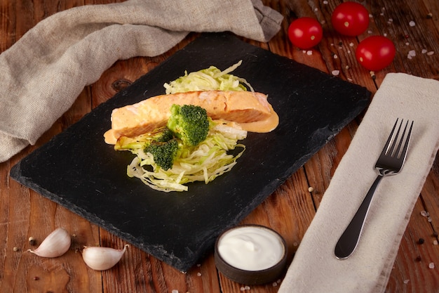 Lachs in cremiger Sauce mit Brokkoli, hölzernem Hintergrund