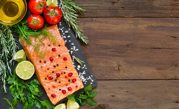 Lachs mit Gemüse und Kräutern auf hölzerner Tischoberansicht mit Kopienraum