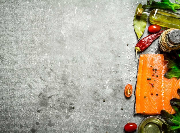 Lachs rohes Filet mit Tomaten, Olivenöl und Gewürzen auf grauem Tisch