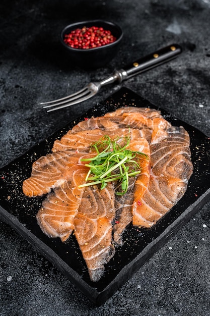 Lachscarpaccio mit Microgreens auf Marmorplatte Schwarzer Hintergrund Ansicht von oben