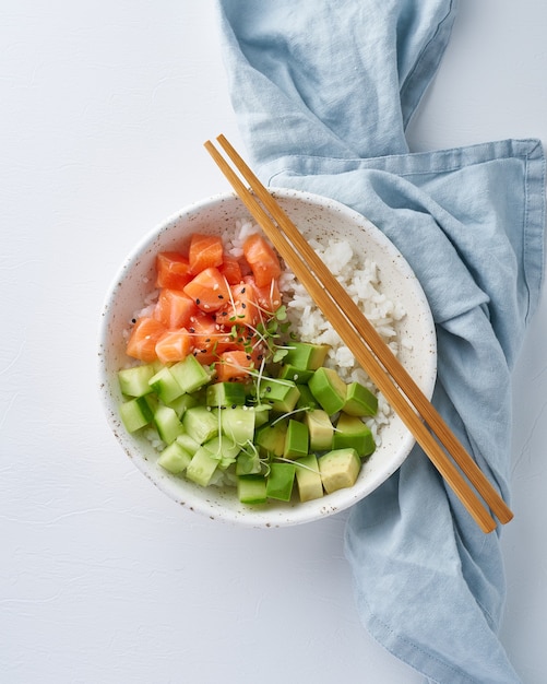 Lachssackschale mit frischem Fisch, Reis, Gurke, Avocado mit schwarzem und weißem Sesam