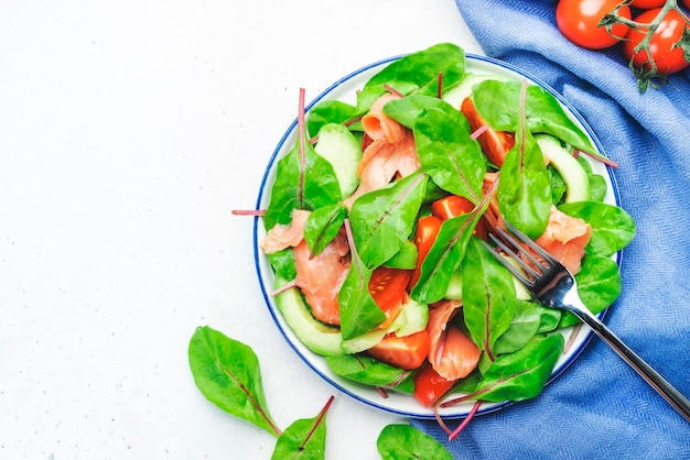 Lachssalat mit Avocado-Rübenblättern, Radicchio-Tomaten, Zitrone und Olivenöl-Dressing Grauer Hintergrund, Draufsicht, Kopienraum