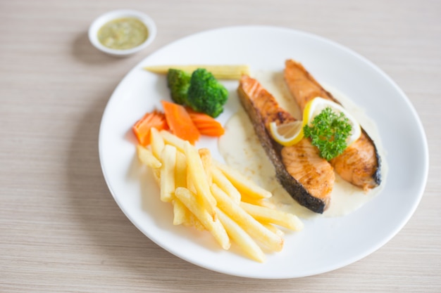 Lachsscheibensteak mit gelber Zitrone verzierte Gemüse