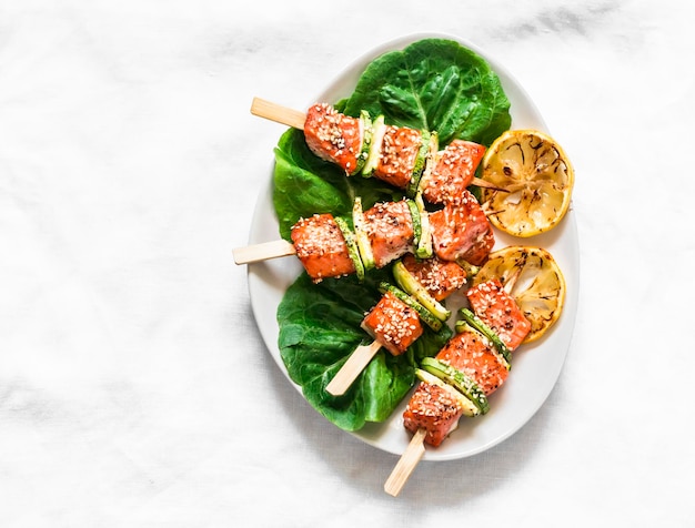 Lachsspieße mit Zucchini und Sesam auf hellem Hintergrund Draufsicht Köstliche Vorspeisen-Tapas-Mittagessen