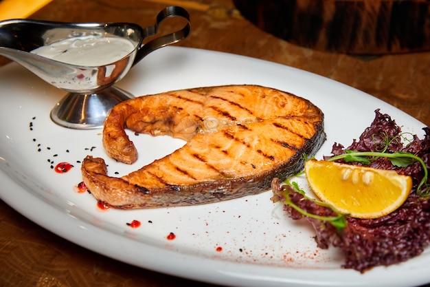 Lachssteak mit Sahnesauce auf einem weißen Teller