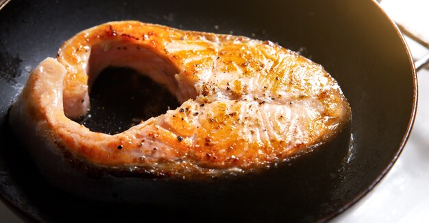 Lachssteak wird in der Pfanne gebraten. Gesunde Omega-3-Nährstoffe. Frischer Fisch nach Hause zubereitet.