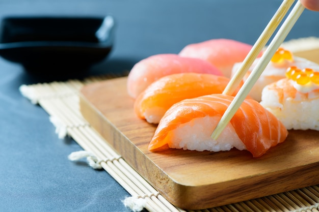 Lachssushi nigiri in den Essstäbchen mit Sashimisushi stellte auf schwarzen Stein, japanisches Lebensmittel ein