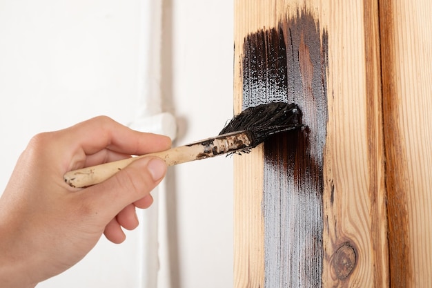 Lackieren einer Tür mit Lack mit einem Pinsel auf einer Holzoberfläche