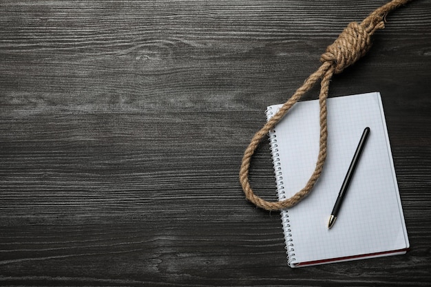 Foto laço de corda e caderno em branco com caneta na mesa de madeira preta plana espaço para texto