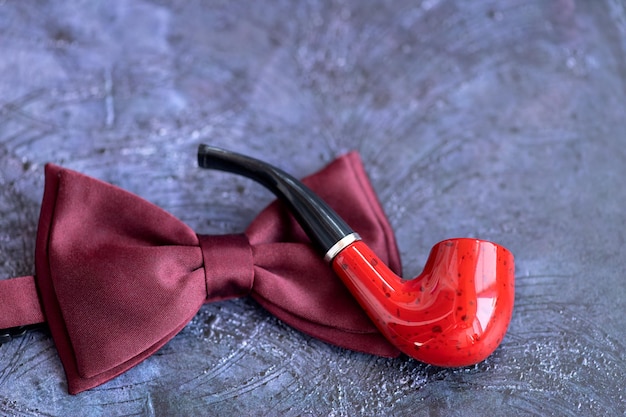 Laço vermelho e cachimbo em um fundo azul Conceito feliz do dia dos pais Flat lay