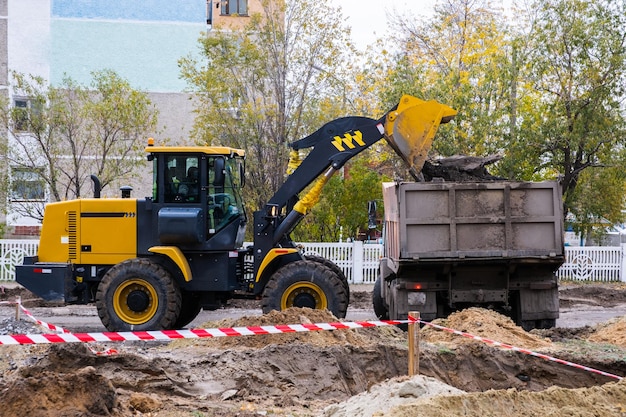 Laden von Erde in einen Muldenkipper durch einen Lader auf einer Baustelle.