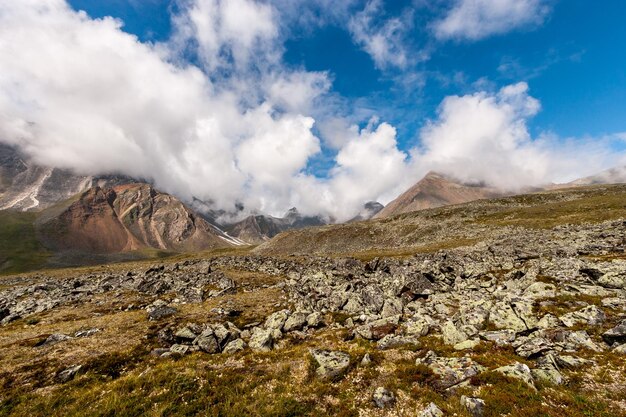 Ladera con piedras grandes amontonadas Rocas con ríos de piedras en la distancia Cielo azul con nubes bajas Horizontal