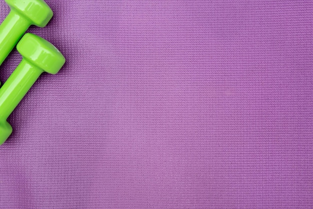 Foto ladie's hanteln über lila fitnessmatte topview sportkonzept