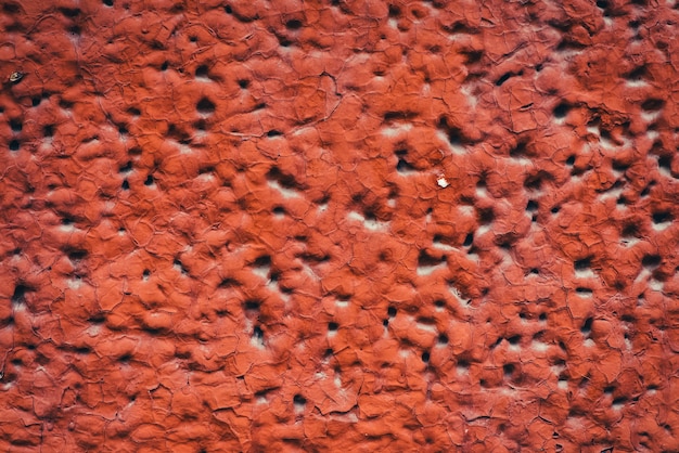 El lado del edificio está pintado de rojo. Textura imperfecta detallada del bloque de espuma aireada con agujeros de primer plano. Fondo de construcción de material espumado en macro con copyspace. Revestimiento decorativo.