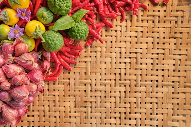 Lado esquerdo do ingrediente tradicional de comida tailandesa, como pimentões secos, cebola roxa pequena, limão e vegetais tailandeses, layout deitado sobre um padrão de madeira tradicional tailandesa de madeira