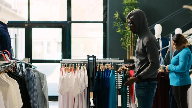 Ladrão afro-americano a roubar uma camisa elegante, a tentar fugir de uma boutique moderna. O guarda-costas asiático apanha o ladrão na porta da loja, pedindo-lhe para devolver as roupas à moda ou chama a polícia.