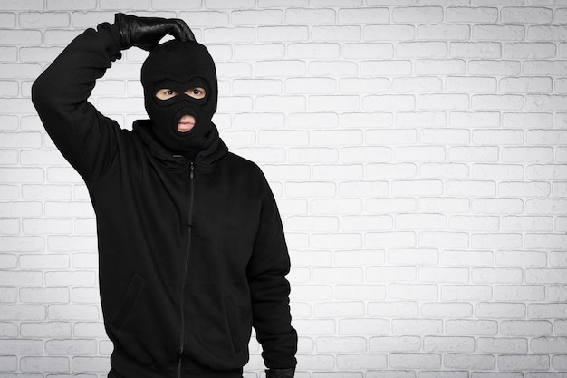 Ladrão com balaclava preta e roupas no fundo