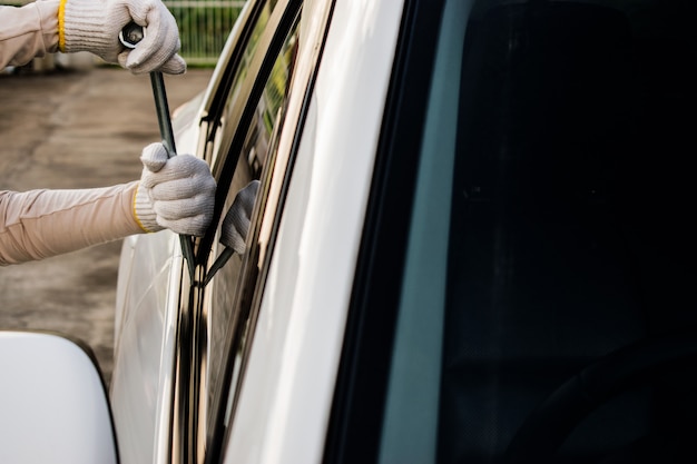 Ladrão está tentando roubar o carro. Um ladrão abrindo a porta do carro quebrando