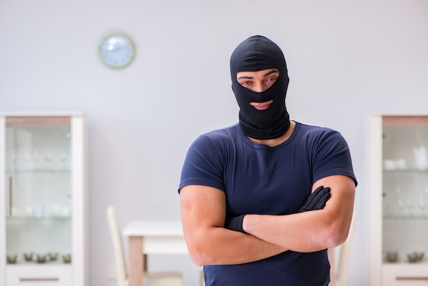 Ladrão usando balaclava roubando coisas valiosas