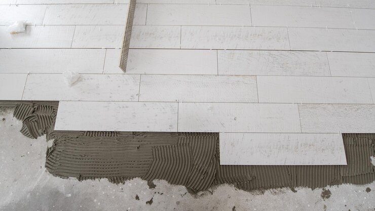 Foto ladrilhos cerâmicos com efeito de madeira e ferramentas para ladrilhar no piso colocação de ladrilhos inacabados instalação de ladrilhos