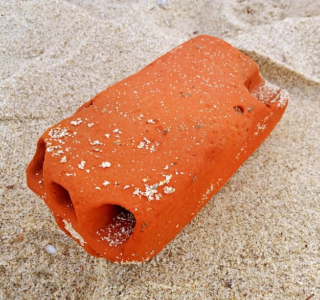 Ladrillo pulido por el mar en la playa de arena