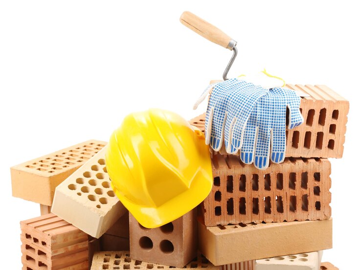 Foto ladrillos nuevos y herramientas de construcción aisladas en blanco