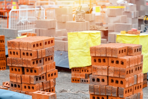 Ladrillos rojos y bloques de hormigón entregados colocados junto al lugar de trabajo listos para albañiles