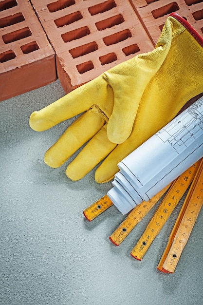 Ladrillos rojos guantes de seguridad planes de construcción medidor de madera sobre el concepto de construcción de fondo de hormigón.