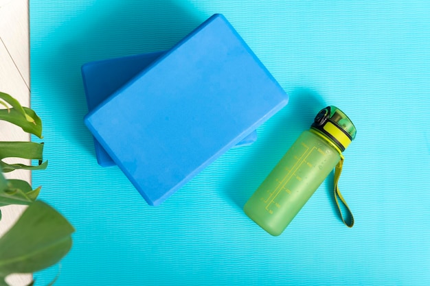 Ladrillos de yoga y botella de agua en la estera de yoga. Instrumentos para gimnasia y estiramientos. Vista superior.