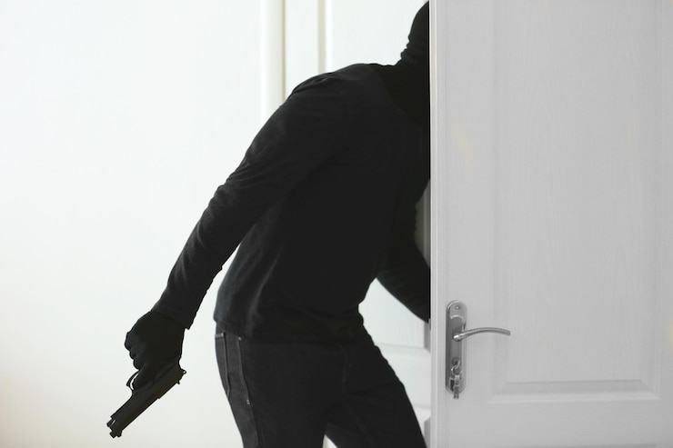 Foto un ladrón con un arma entra en la habitación.