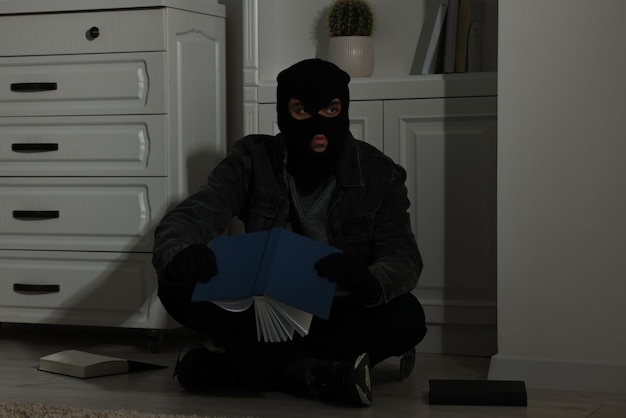 Ladrón buscando dinero cerca de la cómoda en una casa extranjera