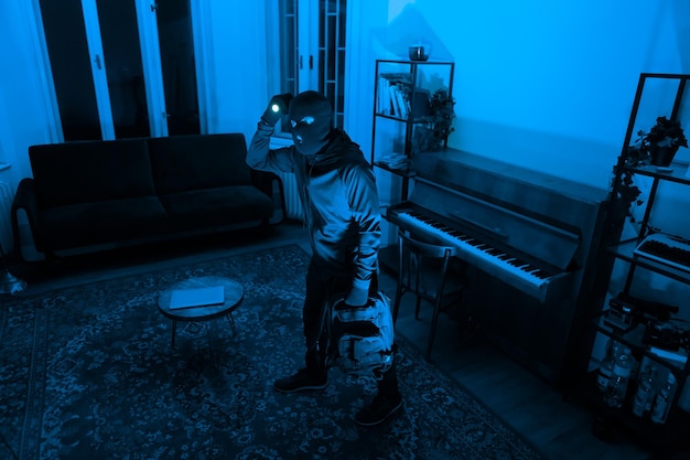 Un ladrón con una linterna en una habitación oscura.