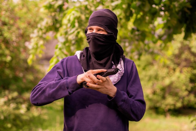 Ladrón en máscara sosteniendo y recargando la pistola al aire libre