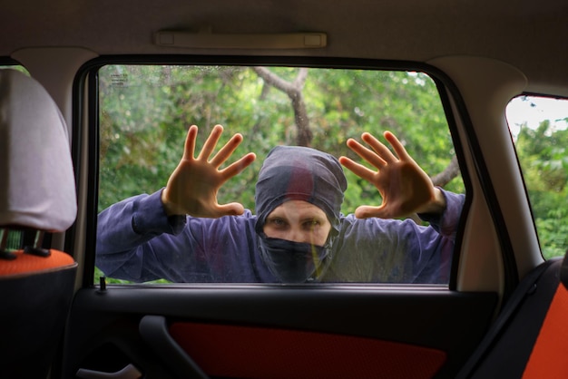 Ladrón parado al lado del auto y tratando de robar cosas.