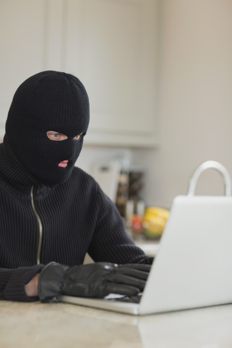 Foto ladrón pirateando una computadora portátil en la cocina