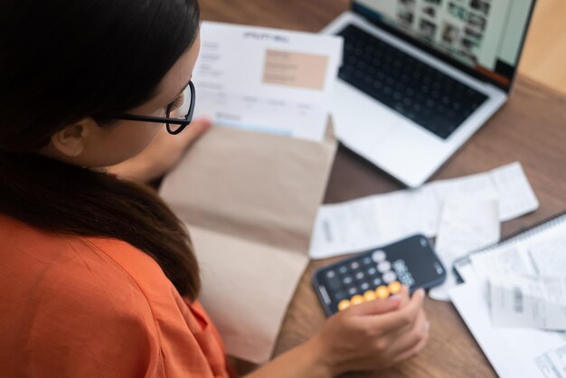 Lady gerencia contas de serviços públicos on-line, segurando recibos de pagamento para uma transação perfeita