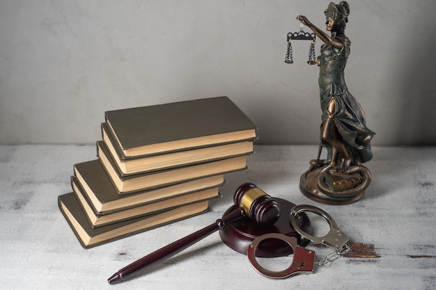 Lady Justice, martillo del juez, libros, esposas en una mesa de madera antigua