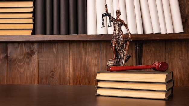 Lady Justice, mazo del juez, libros sobre una mesa de madera antigua