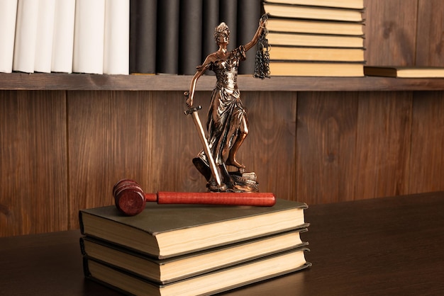 Lady Justice, mazo del juez, libros sobre una mesa de madera antigua