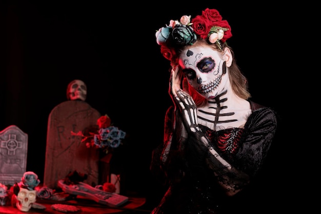 Lady of Dead-Modell mit Santa Muerte-Kostüm, das wie der heilige Schädel von La Cavalera Catrina mit Make-up aussieht. Tragen Sie mexikanische Halloween-Körperkunst, um Dios de los Muertos im Studio zu feiern.