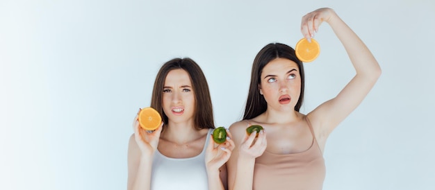 lächeln junge mädchen im sommeroutfit, sie haben spaß und spielen mit saftigen früchten