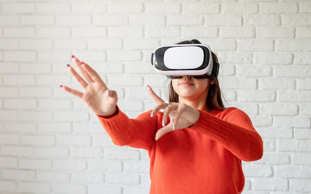 Lächeln Sie glückliche Frau, die Erfahrung mit VR-Headset-Brillen der virtuellen Realität zu Hause mit viel gestikulierenden Händen macht