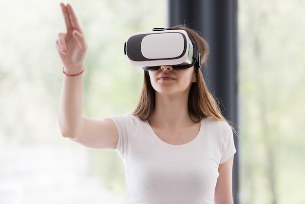 Lächeln Sie glückliche Frau, die zu Hause Erfahrung mit VR-Headset-Brillen der virtuellen Realität macht