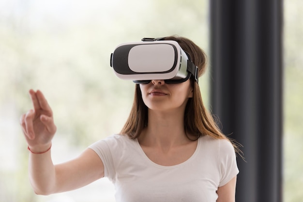 Lächeln Sie glückliche Frau, die zu Hause Erfahrung mit VR-Headset-Brillen der virtuellen Realität macht