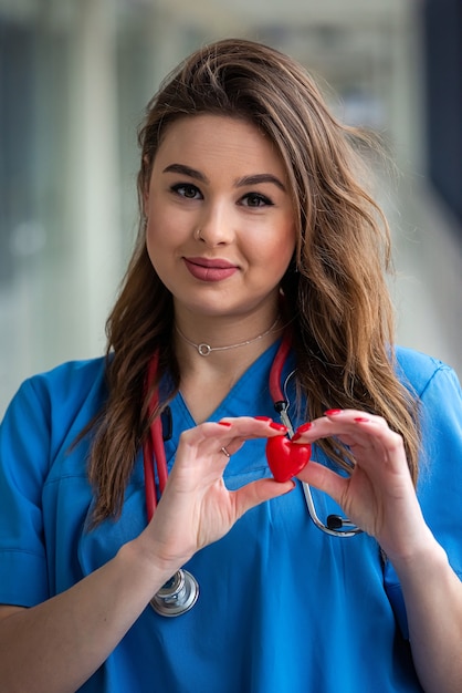 Lächeln Sie hübsche Ärztin in blauer Uniform mit Stethoskop mit Herz. Gesundheitspflege