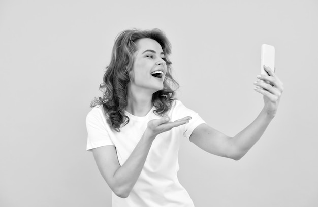 Lächeln Sie immer Konzept des Vlogging Frau gibt Handküssen zum Smartphone Visuelle Kommunikation Glückliches Selfie-Mädchen Blogger gelber Hintergrund Mobile Kommunikation Modernes Leben mit Videoanruf