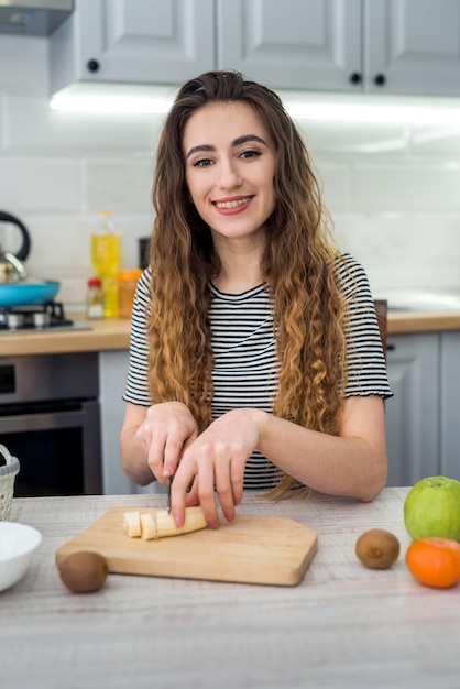 Lächeln Sie junge Frau, die frischen Salat mit Obst in der Küche kocht. Gesunder Lebensstil. Diät